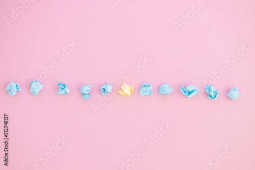 Top view of unique crumpled yellow paper among blue on pink background © ALEXSTUDIO