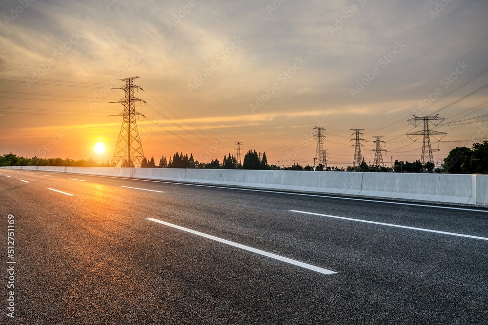 Asphalt road and high voltage power tower scene at sunset. road and electric power background.