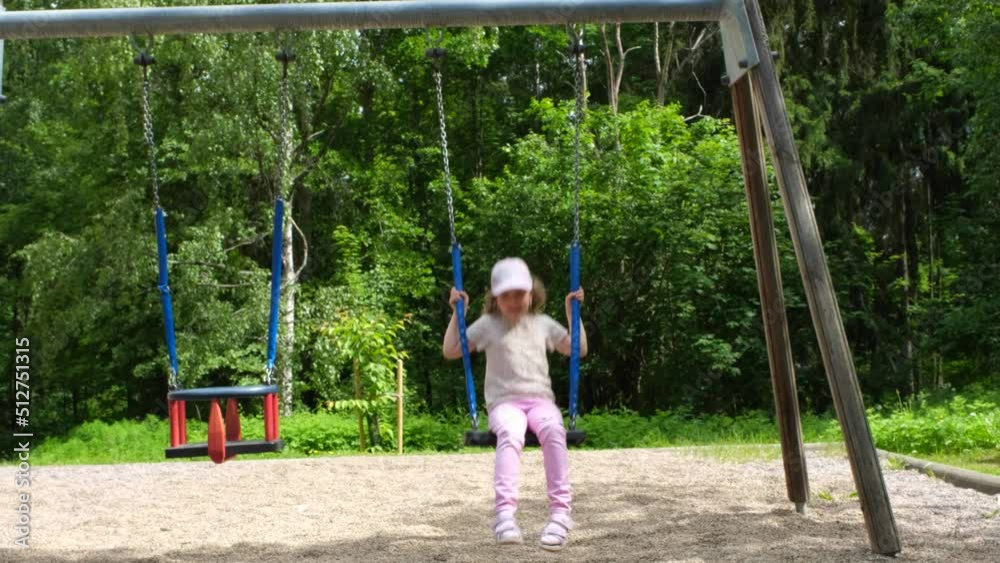 A child, a Caucasian girl swings on a children's swing in a children's city playground. A child, a Caucasian girl swings on a children's swing in a children's city playground.