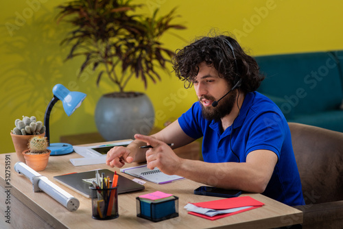 Blond male working from home with headphones using wireless internet on laptop, man call center agent or telemarketer