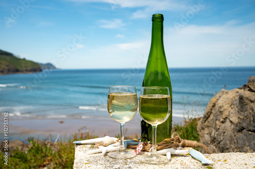 Tasting of txakoli or chacolí slightly sparkling very dry white wine produced in the Spanish Basque Country, served outdoor with view on Bay of Biscay, Atlantic Ocean. photo