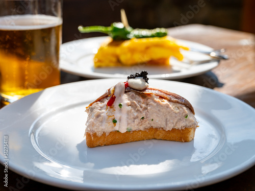 Sunny day in San Sebastián, typical food and drink in bars of Basque Country, pinchos or pinxtos, small slices of bread with different toppings and glass of beer, lunch in Spain