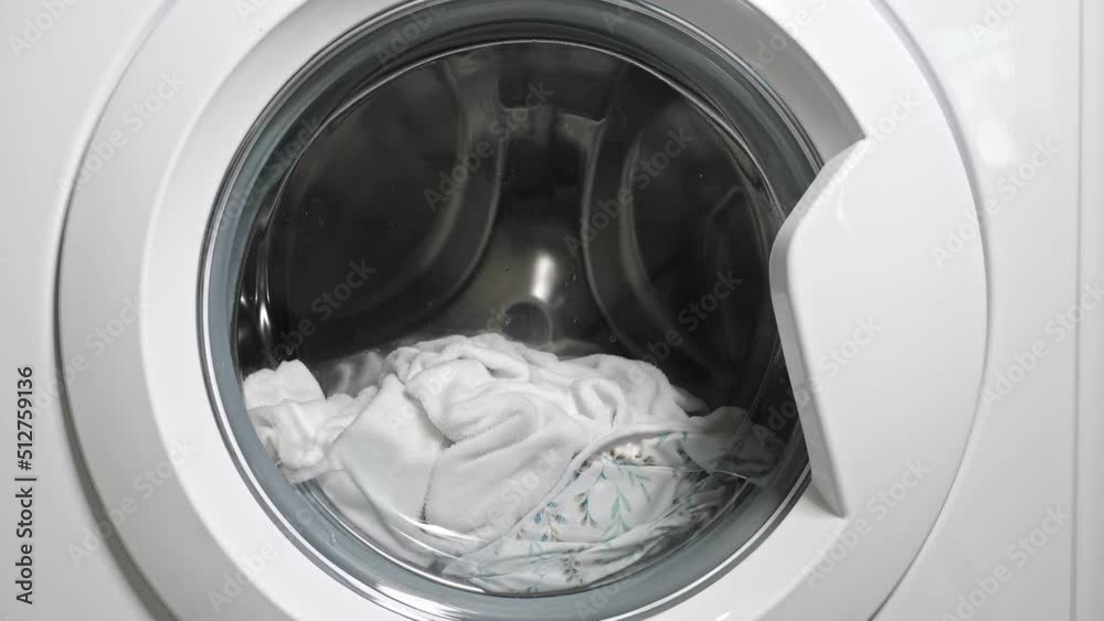 Collecting clean water in white washing machine. Washing machine metal drum spins dirty laundry and stops then rotates again with dirty linen closeup, fast motion Collecting clean water in white washing machine. Washing machine metal drum spins dirty laundry and stops then rotates again with dirty linen closeup, fast motion
