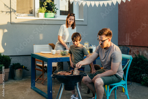 family of three preparing barbecue in home backyard