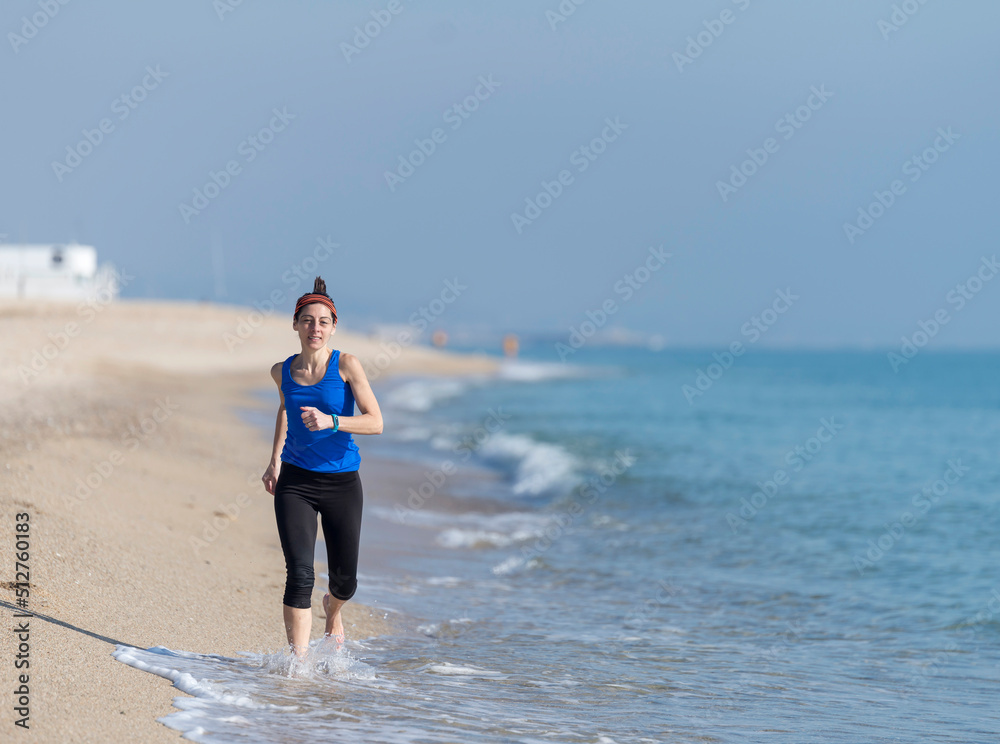 Front view of women jogging on beach close to water Front view of women jogging on beach close to water