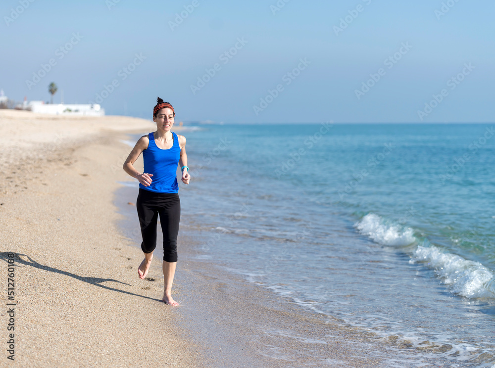 Front view of women jogging on beach close to water