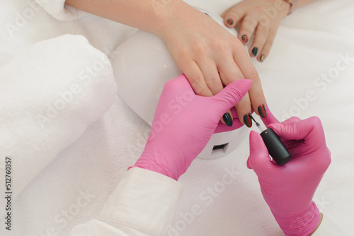 Closeup of manicure master coloring client s nails in beauty salon