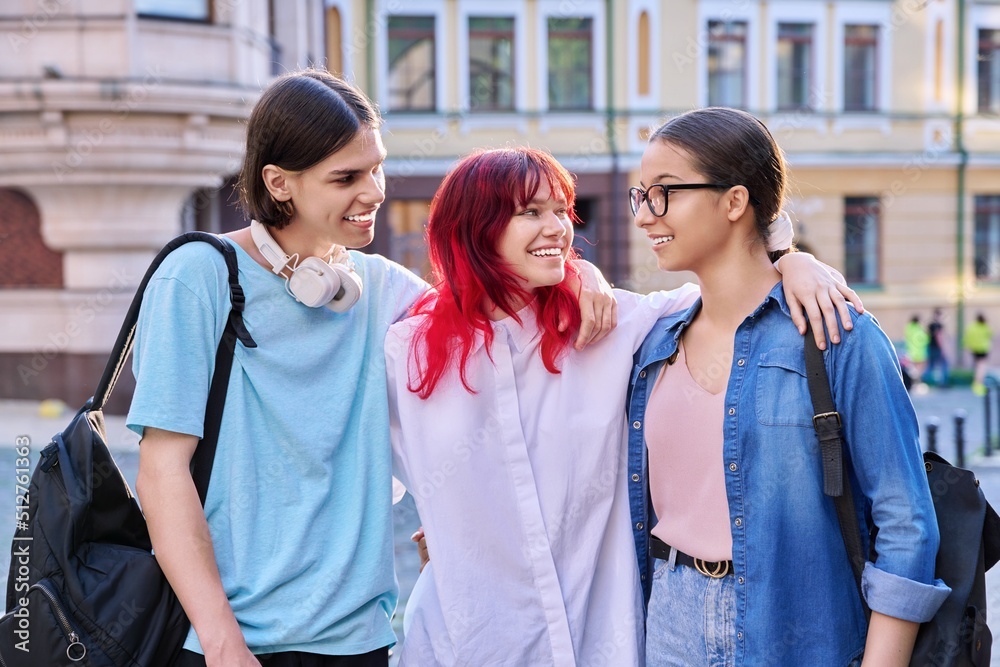 Happy smiling teenage friends hugging outdoor, on city street