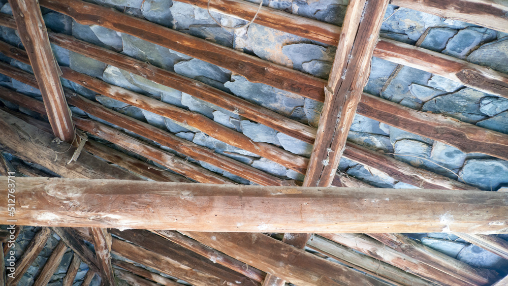 Vigas de madera y placas de pizarra en tejado rústico de casa rural