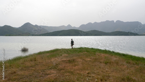 Silueta de hombre en orilla de lago frente a horizonte monta  oso