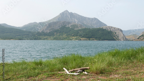 Lago rodeado de montañas rocosas y praderas de hierba photo