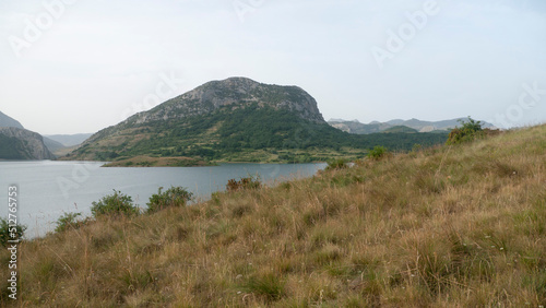Lago rodeado de montañas rocosas y praderas de hierba photo