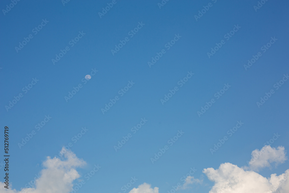 Picture of a blue sky with white clouds and a moon during the day. Picture of a blue sky with white clouds and a moon during the day.