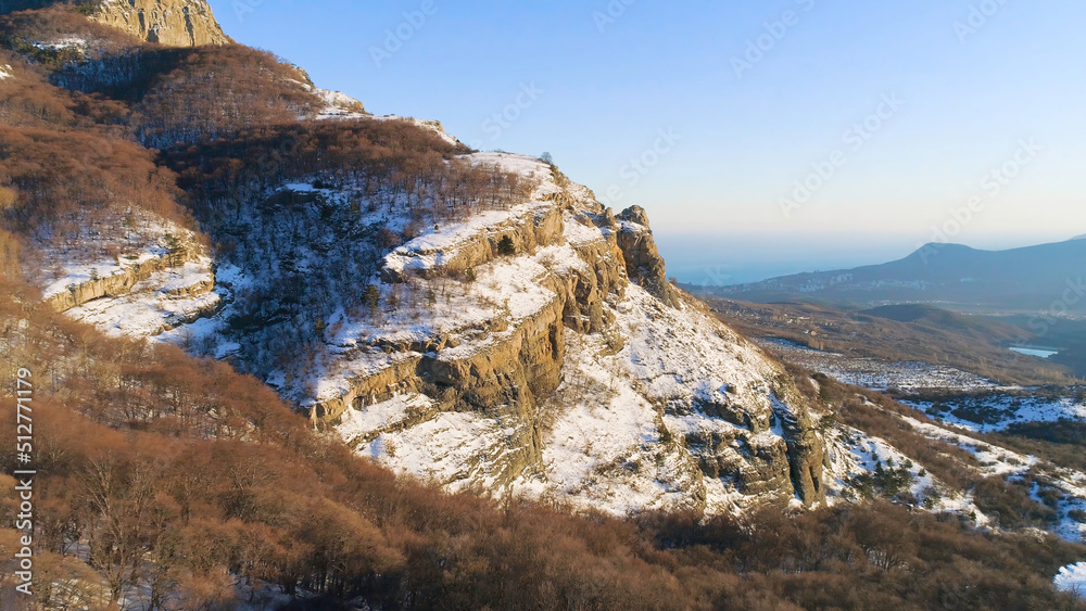Beautiful mountain panorama with rock ledges and snow. Shot. Rock with small amount of snow on background of mountain panorama on sunny day