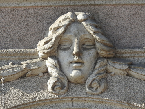 Stone head of woman decorative element on the facade of the building