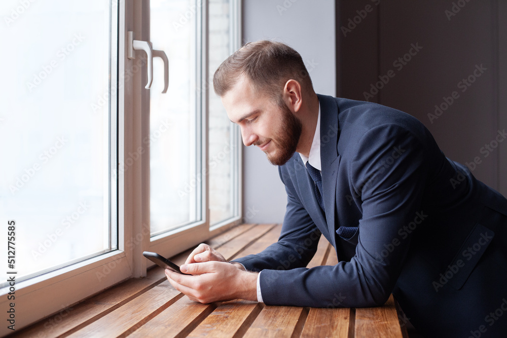 Businessman using smartphone and smiling. Young business executive with mobile phone portrait Businessman using smartphone and smiling. Young business executive with mobile phone portrait