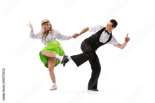 Excited young couple of dancers in vintage retro style outfits dancing social dance isolated on white background. Art, music, fashion, style concept