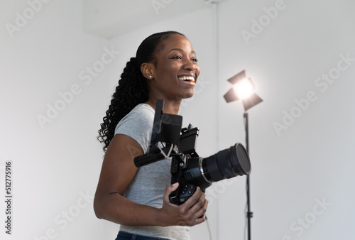 Fotobehang African American Female Videographer Posing with Video Camera in Hand on Film Set