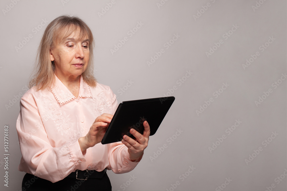Senior woman reading a message, e-book or information on her tablet computer