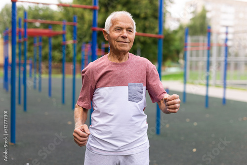 Old man running beside outdoor sports ground