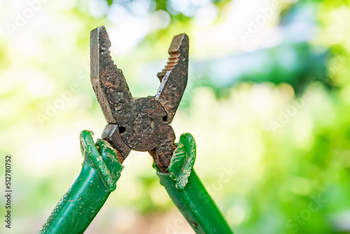 Rusted pliers. Old rusty pliers open on blurred natural background. Old working tool. Selective soft focus.