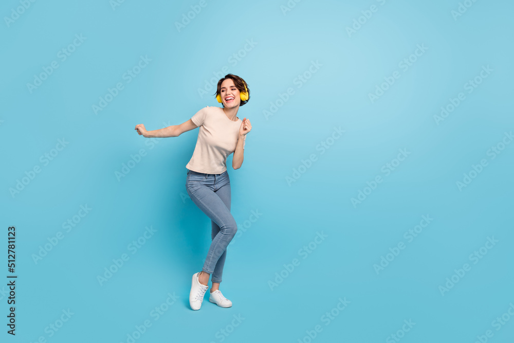 Photo of pretty cute lady dressed beige t-shirt earphones dancing empty space isolated blue color background