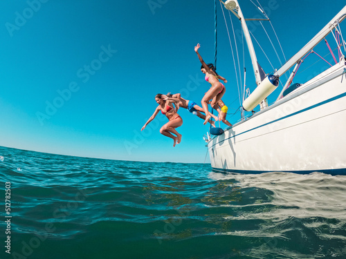 Photography Happy friends diving from sailing boat into the sea - Focus on left girl face