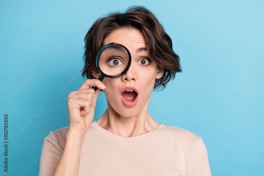 Photo of young impressed young lady using magnifying glass play detective catch spy isolated on blue color background Photo of young impressed young lady using magnifying glass play detective catch spy isolated on blue color background
