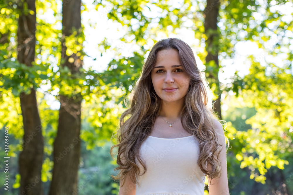 Beautiful young Russian girl dressed in a white dress, walks through the forest among the oaks in the rays of the sunset Beautiful young Russian girl dressed in a white dress, walks through the forest among the oaks in the rays of the sunset