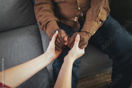 Cropped shot of a senior African american man holding hands with a nurse. Female healthcare worker holding hands of senior man at care home, focus on hands.
