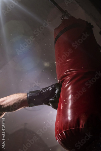 Fototapeta Naklejka Na Ścianę i Meble -  Close-up hand of boxer at the moment of impact on punching bag