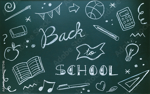 Blackboard written with chalk with message and school supplies. Back to school concept