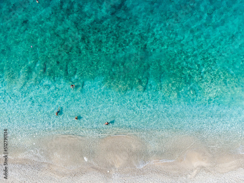 Aerial drone view of swimmers in the sea at summer. Tourists diving and swimming in the water. Transparent sea water in bay. 