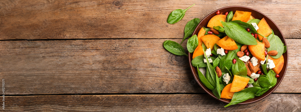 Delicious persimmon salad served on wooden table, top view with space for text. Banner design Delicious persimmon salad served on wooden table, top view with space for text. Banner design