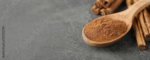 Aromatic cinnamon powder and sticks on grey table, closeup view with space for text. Banner design photo