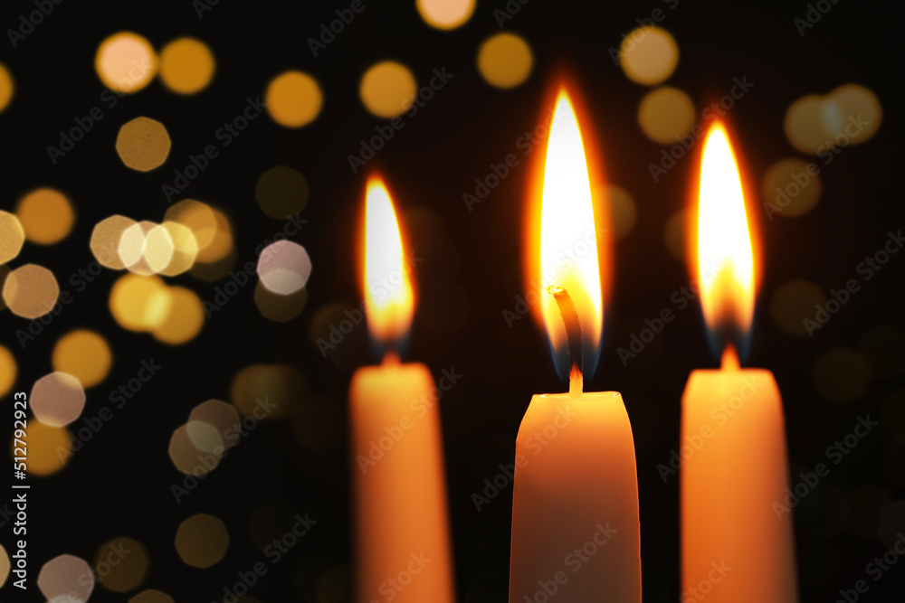 Burning candles on dark background with blurred lights, closeup. Bokeh effect Burning candles on dark background with blurred lights, closeup. Bokeh effect