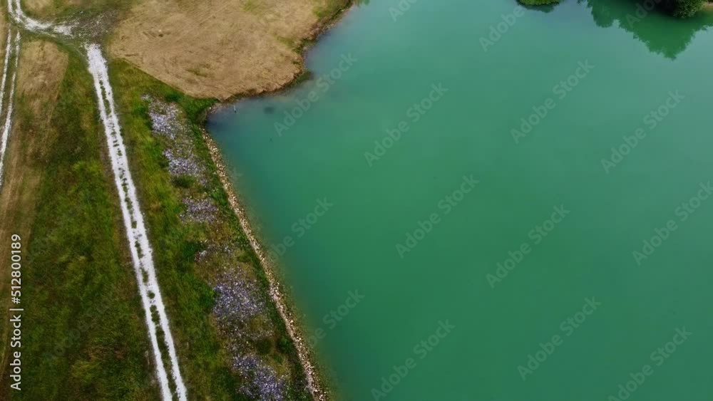 Retenue d'eau vue du ciel avec son chemin la traversant de part et d'autres et son lac. Digue formée de végétation retenant l'eau du lac.