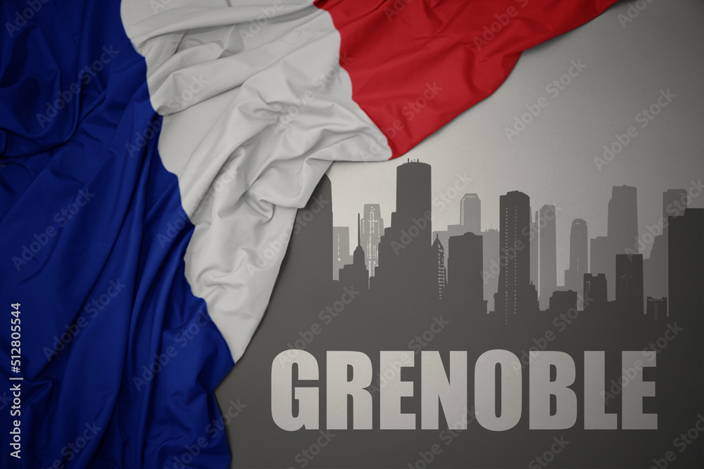 abstract silhouette of the city with text Grenoble near waving national flag of france on a gray background.