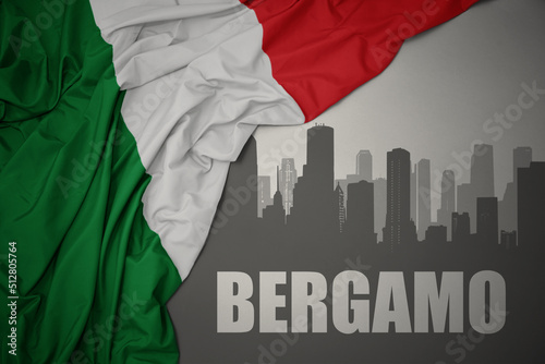 abstract silhouette of the city with text Bergamo near waving national flag of italy on a gray background.