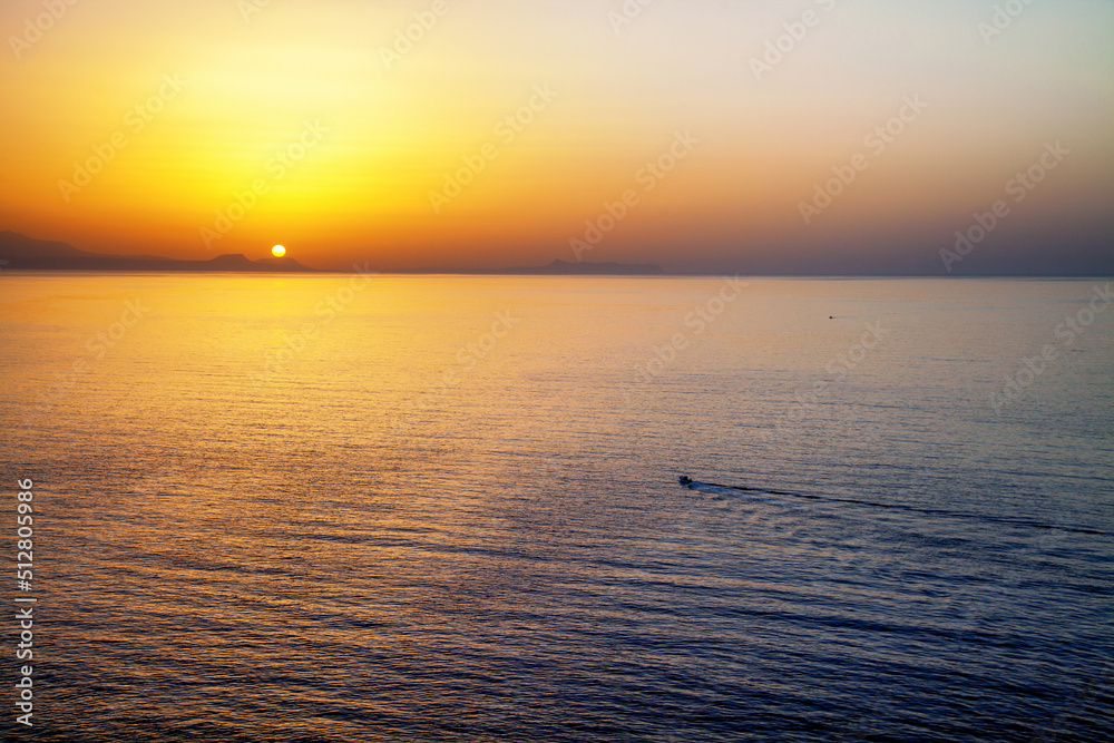 Beautiful colorful sunset and small boat on the sea