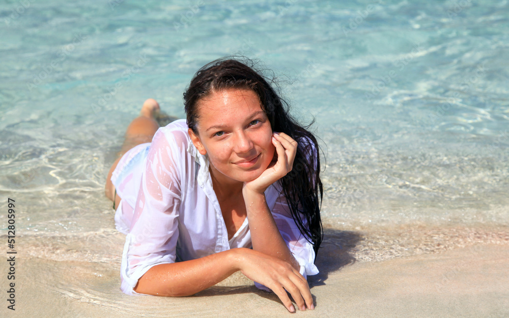 Girl in white shirt posing lying in sea in Elafonisi beach in Crete island at Greece
