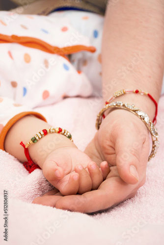 Indian Mother holds her baby's tiny hand on her palm on a delicate pink blanket. Family in bracelets and traditional jewelry. Love, security and warmth concept