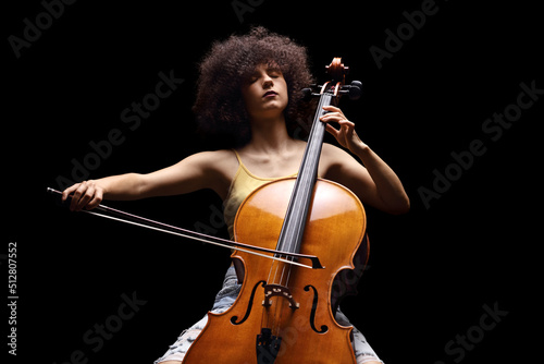 Fototapeta Female artist playing a cello isolated on black