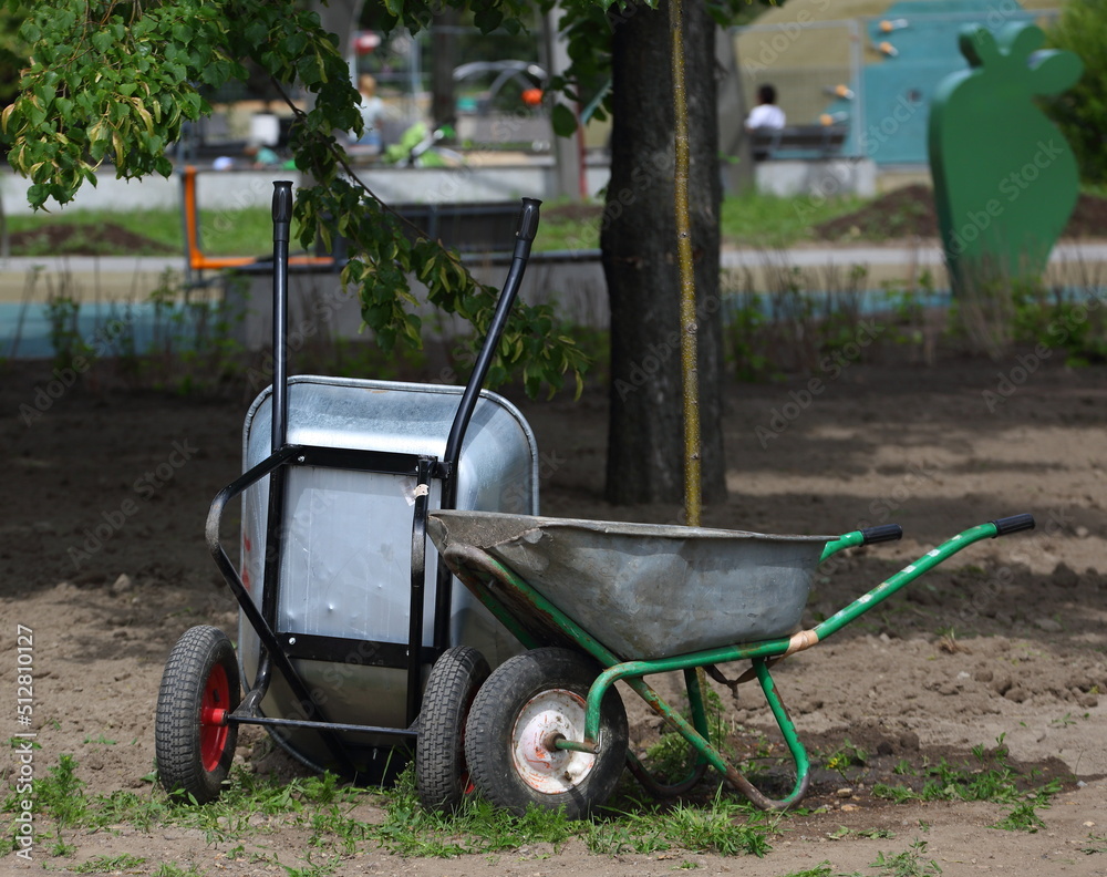 Fototapeta premium Two metal two-wheeled wheelbarrows in the garden