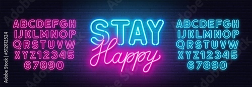 Stay Happy neon quote on a brick wall.