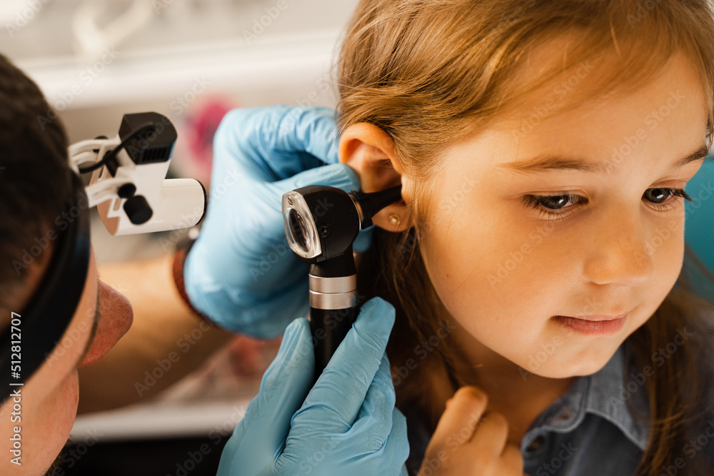 Closeup examination of childs ear with otoscope. Otoscopy. Visit to