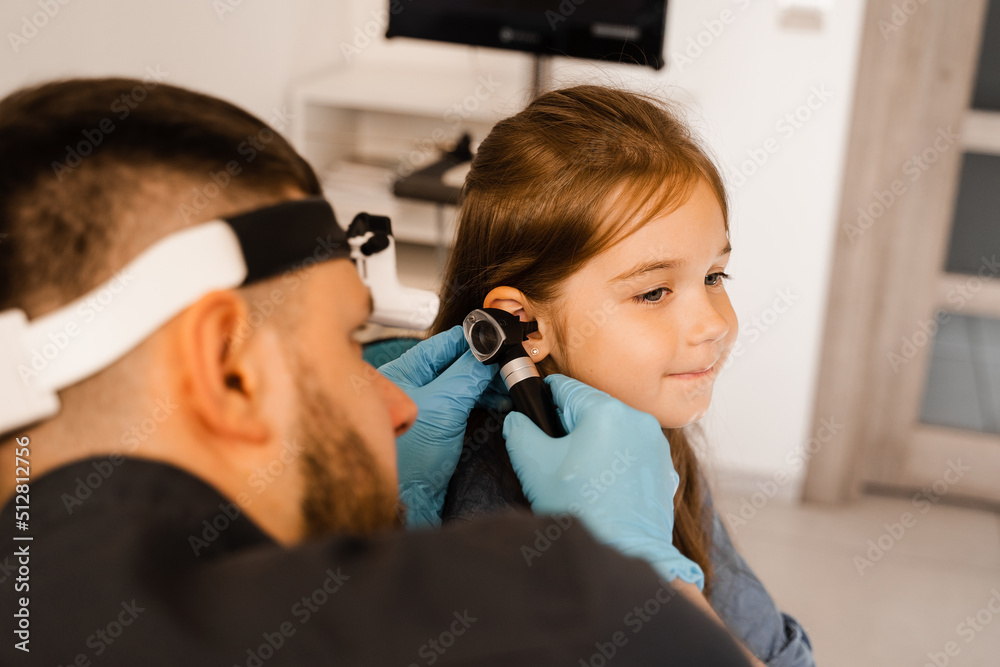 ENT doctor with otoscope. Otoscopy. Pediatrician otolaryngologist looks through otoscope the
