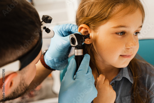 ENT doctor otolaryngologist looks through otoscope the ears of a little girl. Otoscopy. Treatment child ear pain. photo