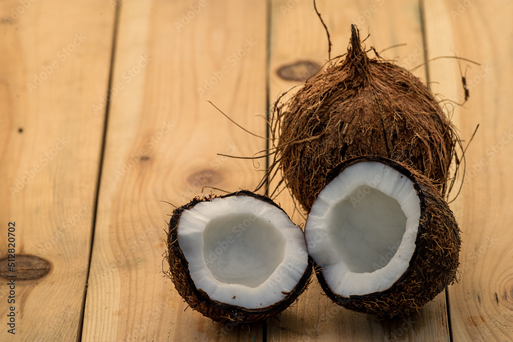 Ripe hole and half cut coconut on a old wooden background. Coconut cream and oil. Ripe hole and half cut coconut on a old wooden background. Coconut cream and oil.
