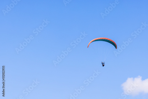 Paraglider flying high up at a blue sky